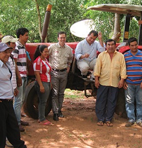 Mark Coffey (center) meets with a group of 75 Paraguayan farmers. These farmers have formed an association that sells to BioExport. They have also banded together to purchase the tractor pictured. They are hoping that their livelihoods will improve, and that they can one day become a cooperative. Photo © Global Partnerships.