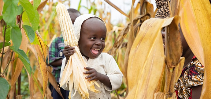 Smiling child holding corn