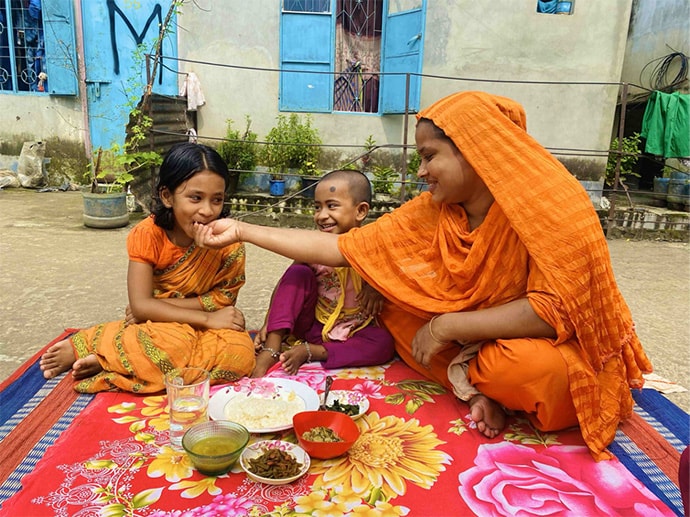 Mother feeding her children seated on blanket outdoors
