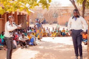 Two actors in play outside with audience