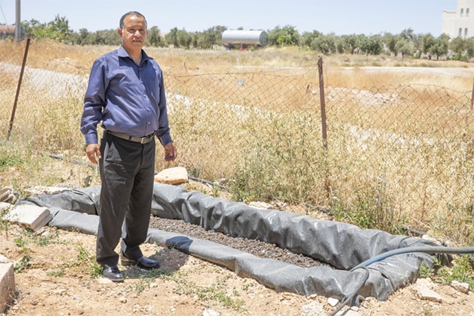 Photo of Ahmad Al Habahbeh next to greywater system
