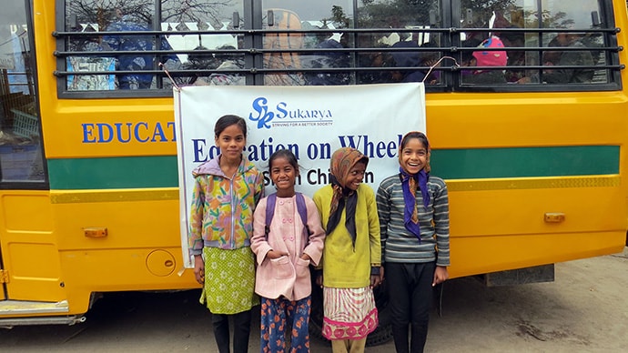 Photo of smiling students in front of bus