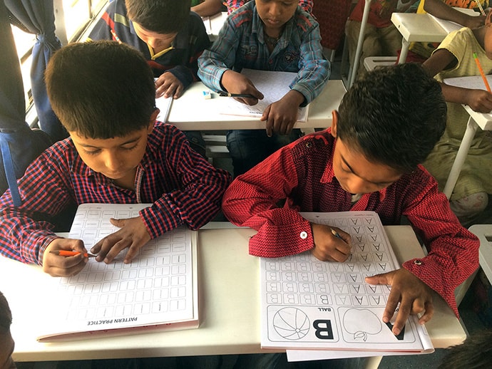 Overhead view of students writing at desk