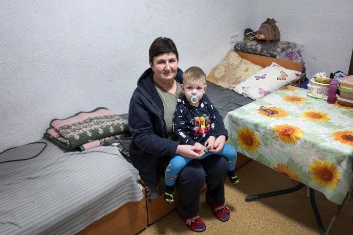 Photo of Lydmyla and her grandson sitting on bed