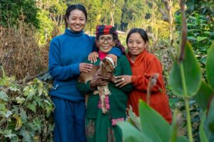 Photo of three women holding a small goat