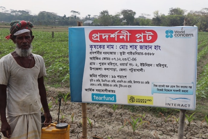 Farmer Shajahan posing in field next to sign