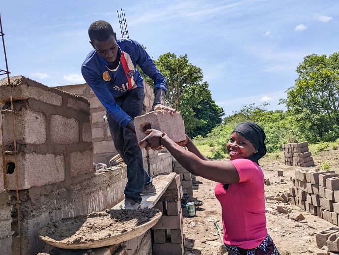 Photo of woman passing a man a brick