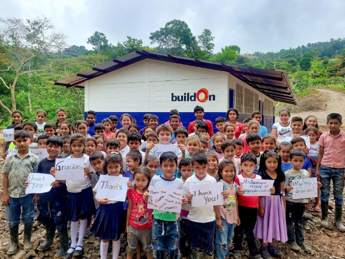 Group photo of Sandra and her students posed in front of buildOn school